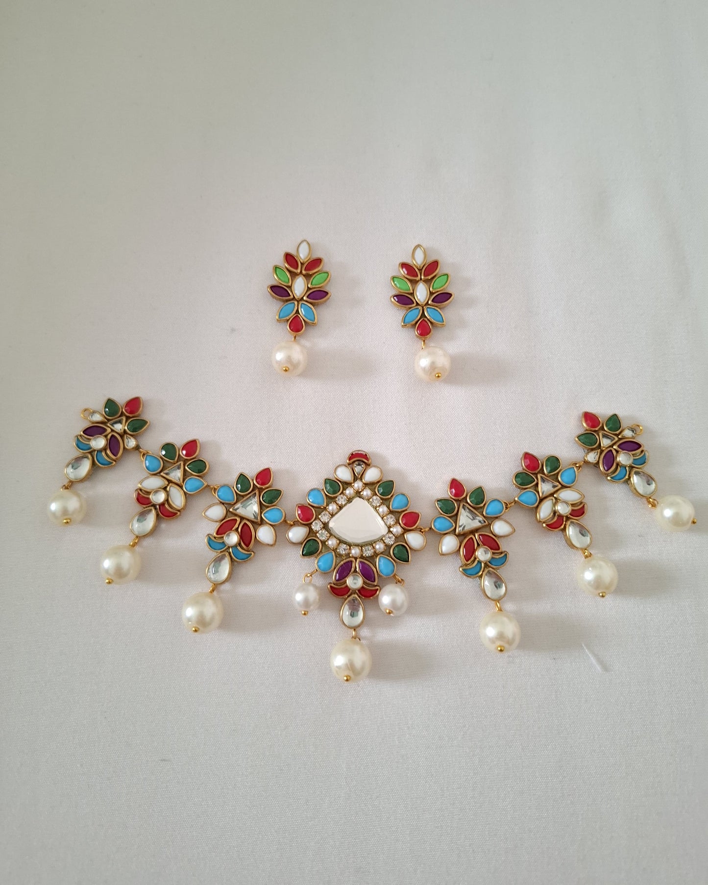 Set of decorative earrings with pearls and gemstones on a light gray background