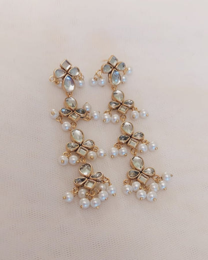 Pair of gold and pearl earrings on a beige background