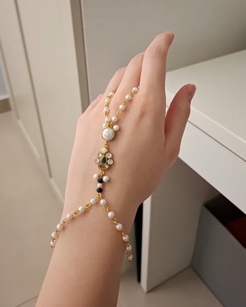 Hand wearing a delicate pearl bracelet with a neutral background